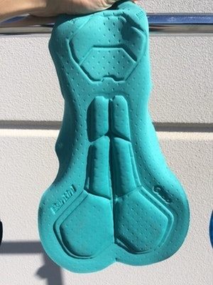 Blue cycling chamois pad hanging on a rail.