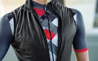 Close-up of a cyclist wearing a black vest over a patterned cycling jersey.