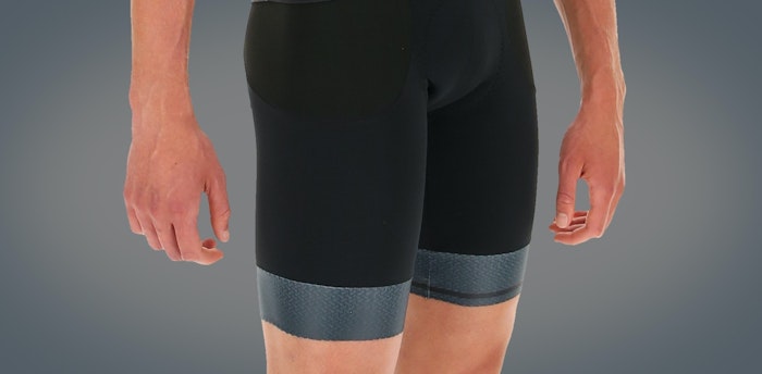 Close-up of person wearing black Impact bib shorts against a gray background.