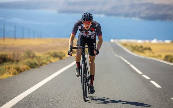 Cyclist Riding on an Open Road with Scenic Ocean View in Santini Gear