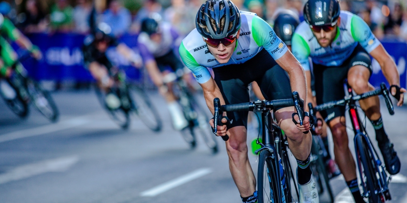 Cyclists in a race wearing helmets and cycling jerseys, showcasing intense competition and focus.