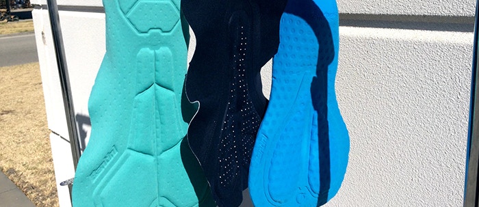 Three blue and black cycling chamois pads hanging to dry