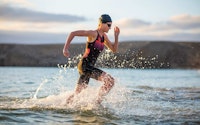 Triathlete running out of the water during a race.