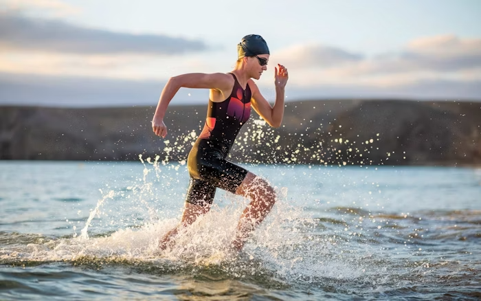 Triathlete Running Through Water in a Swim Cap and Tri Suit During a Race